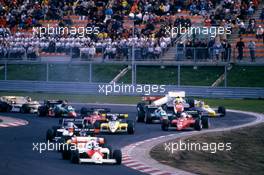 Alain Prost (FRA) McLaren Mp4/2 Tag Porsche 1st position lead the group at start.Ayrton Senna da Silva  (BRA) Toleman TG 184 Hart crashes into Keke Rosberg (FIN) Williams Fw09B Honda
