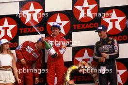 Alain Prost (FRA) McLaren 1st position Niki Lauda (AUT) McLaren 2nd position Nigel Mansell (GBR) Lotus 3rd position celebrates podium