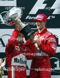 12.05.2002 Spielberg, Oesterreich, F1 in Spielberg am Sonntag, Michael Schumacher (1ter) übergiebt Rubens Barrichello (2ter) den Siegerpokal nach dem Rennen auf dem Podium, Formel 1 Grand Prix (GP) von Austria 2002 auf dem A1 Ring, Österreich, Zeltweg, Spielberg c xpb.cc Email: info@xpb.cc, weitere Bilder auf der Datenbank: www.xpb.cc