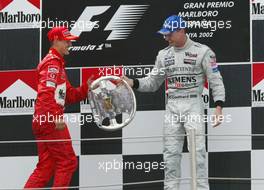 28.04.2002 Barcelona, Spanien, Barcelona, Podium nach dem Formel 1 Grand Prix (GP) von Spanien 2002, Michael Schumacher (1ter) und David Coulthard (3ter) - DC gibt MS seinen Pokal zurück den kurz hochgehoben hatte, Sonntag, Box c xpb.cc Email: info@xpb.cc, weitere Bilder auf der Datenbank: www.xpb.cc