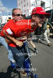 18.07.2002 Magny-Cours, Frankreich, F1 in Frankreich, Donnerstag, Michael Schumacher und Rubens Barrichello fahren gemeinsam mit dem Elektro-Scooter vom Motorhome zu der Box, im Paddock Bereich, Formel 1 Grand Prix (GP) von Frankreich 2002 (France, Nevers Magny - Cours) c xpb.cc - weitere Bilder auf der Datenbank unter www.xpb.cc - Email: info@xpb.cc