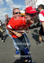 18.07.2002 Magny-Cours, Frankreich, F1 in Frankreich, Donnerstag, Michael Schumacher und Rubens Barrichello fahren gemeinsam mit dem Elektro-Scooter vom Motorhome zu der Box, im Paddock Bereich, Formel 1 Grand Prix (GP) von Frankreich 2002 (France, Nevers Magny - Cours) c xpb.cc - weitere Bilder auf der Datenbank unter www.xpb.cc - Email: info@xpb.cc