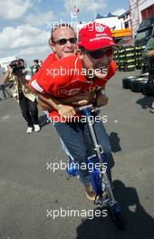 18.07.2002 Magny-Cours, Frankreich, F1 in Frankreich, Donnerstag, Michael Schumacher und Rubens Barrichello fahren gemeinsam mit dem Elektro-Scooter vom Motorhome zu der Box, im Paddock Bereich, Formel 1 Grand Prix (GP) von Frankreich 2002 (France, Nevers Magny - Cours) c xpb.cc - weitere Bilder auf der Datenbank unter www.xpb.cc - Email: info@xpb.cc