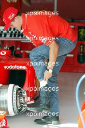 15.08.2002 Budapest, Ungarn, F1 in Budapest, Donnerstag, Michael Schumacher (Ferrari) in der Box - nimmt Platz in seinem Wagen und testet den Sitz - hier zieht er seine blau/schwarzen Cowboystifel aus, Formel 1 Grand Prix (GP) von Ungarn 2002 (Hungary, Budapest) c xpb.cc - weitere Bilder auf der Datenbank unter www.xpb.cc - Email: info@xpb.cc