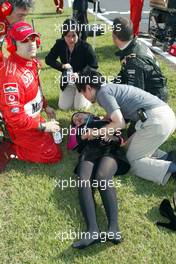 13.10.2002 Suzuka, Japan, F1 in Japan, Sonntag, vor dem Start zum GP von Japan, ein Gridgirl ist neben Michael Schumacher s Wagen in Ohnmacht gefallen (Hitze) und wird von Mechanikern betreut, Suzuka Circuitland, 2002 F1 Japanese Grand Prix - (Japan, Formel 1, GP). c xpb.cc - weitere Bilder auf der Datenbank unter www.xpb.cc - Email: info@xpb.cc