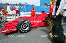 22.05.2002 Monte Carlo, Monaco, F1 in Monaco, Mittwoch, Vorbereitungen in Monte Carlo, hier im Hafen, das Ferrari Team schiebt den F1 Wagen durch den regulären Verkehr zur technischen Abnahme - und wird von Schaulustigen hier mit Hund beobachtet, Formel 1 Grand Prix (GP) von Monaco 2002 in Monte Carlo, Monaco c xpb.cc Email: info@xpb.cc, weitere Bilder auf der Datenbank: www.xpb.cc