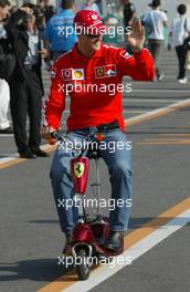 09.10.2003 Suzuka, Japan, F1 in Japan, Donnerstag, Michael Schumacher (D, Ferrari) auf dem Weg zur Pressekonferenz auf einem Elektro Scooter - Formel 1 Grand Prix (GP) von Japan 2003 (Suzuka Race Circuit) - Weitere Bilder auf www.xpb.cc, eMail: info@xpb.cc - Belegexemplare senden. Abdruck ist honorarpflichtig. c Copyrightnachweis: xpb.cc