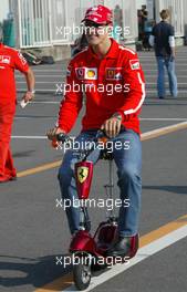 09.10.2003 Suzuka, Japan, F1 in Japan, Donnerstag, Michael Schumacher (D, Ferrari) auf dem Weg zur Pressekonferenz auf einem Elektro Scooter - Formel 1 Grand Prix (GP) von Japan 2003 (Suzuka Race Circuit) - Weitere Bilder auf www.xpb.cc, eMail: info@xpb.cc - Belegexemplare senden. Abdruck ist honorarpflichtig. c Copyrightnachweis: xpb.cc