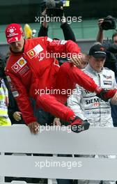 26.09.2003 Indianapolis, USA, F1 in Indy (USA), Freitag, Michael Schumacher (D, Ferrari) springt über die Leitplanke, nach dem Qualyfying, Gruppenbild mit Juan-Pablo Montoya (CO, BMW WilliamsF1), Bernie Ecclestone, Michael Schumacher (D, Ferrari), Kimi Raikkonen, (FIN, McLaren Mercedes) - 2003 United States Grand Prix (Indianapolis Motor Speedway, USGP, Formel 1, Brickyard) - Weitere Bilder auf www.xpb.cc, eMail: info@xpb.cc - Belegexemplare senden. Abdruck ist honorarpflichtig. c Copyrightnachweis: xpb.cc