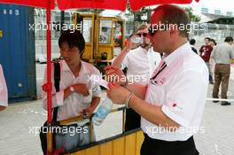 15.07.2004 Shanghai, China,  DTM, Thursday, An Audi team member looks interesting at a pen offered by one of the many local salesman offering their ware to anybody on the street - DTM Season 2004 at Pu Dong Street Circuit Shanghai (Deutsche Tourenwagen Masters)