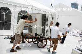 15.07.2004 Shanghai, China,  DTM, Thursday, Local worksman bringing airconditioning units for cooling in the DTM pitbox tents - DTM Season 2004 at Pu Dong Street Circuit Shanghai (Deutsche Tourenwagen Masters)