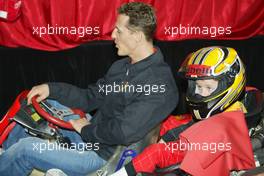 04.03.2004 Melbourne, Australia, F1, Thursday, March, Shell Press Conference with Michael Schumacher, GER, Ferrari sits in a two seater go kart with a child. in the "Shell House", Formula 1 World Championship, Rd 1, Australian Grand Prix. www.xpb.cc, EMail: info@xpb.cc - copy of publication required for printed pictures. Every used picture is fee-liable. c Copyright: xpb.cc
