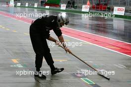 16.09.2005 Klettwitz, Germany,  Mechanic swipping the pitlane in front of the pitbox to remove the standing water - DTM 2005 at Lausitzring (Deutsche Tourenwagen Masters)