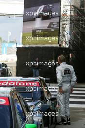 17.09.2005 Klettwitz, Germany,  Mika Häkkinen (FIN), Sport Edition AMG-Mercedes, AMG-Mercedes C-Klasse, watches a big TV screen to see how Laurent Aiello (FRA), Opel Performance Center, Opel Vectra GTS V8, is doing - DTM 2005 at Lausitzring (Deutsche Tourenwagen Masters)