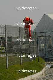 16.10.2005 Shanghai, China,  Michael Schumacher, GER, Ferrari climbs a fence before running back to the pits after crashing during the Installation lap - October, Formula 1 World Championship, Rd 19, Chinese Grand Prix, Sunday Race