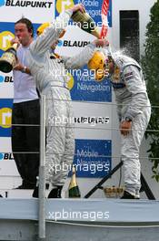 23.07.2006 Nurnberg, Germany,  Podium, Mika Häkkinen (FIN), AMG-Mercedes, Portrait (3rd, left), gives race winner Bruno Spengler (CDN), AMG-Mercedes, Portrait (1st, right) a champaign shower - DTM 2006 at Norisring (Deutsche Tourenwagen Masters)