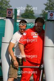 15.07.2006 Magny Cours, France,  Michael Schumacher (GER), Scuderia Ferrari, sneeking through the security gates together with one of his mechanics - Formula 1 World Championship, Rd 11, French Grand Prix, Saturday