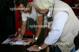 15.07.2006 Magny Cours, France,  Michael Schumacher (GER), Scuderia Ferrari, Portrait, signing autographs for a journalist - Formula 1 World Championship, Rd 11, French Grand Prix, Saturday