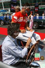 16.07.2006 Magny Cours, France,  Michael Schumacher (GER), Scuderia Ferrari, Portrait, signing autographs for the driver of his car during the driver parade - Formula 1 World Championship, Rd 11, French Grand Prix, Sunday