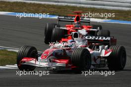 30.07.2006 Hockenheim, Germany,  Takuma Sato (JPN), Super Aguri F1, SA06 leads Tiago Monteiro (POR), Midland MF1 Racing, Toyota M16 - Formula 1 World Championship, Rd 12, German Grand Prix, Sunday Race