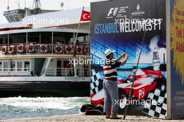 23.08.2006 Istanbul, Turkey,  A fisher stands in front of an advertising banner in downtown Istanbul - Formula 1 World Championship, Rd 14, Turkish Grand Prix, Wednesday