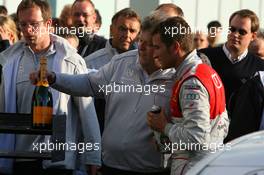 25.10.2009 Hockenheim, Germany,  Norbert Haug (GER), Sporting Director Mercedes-Benz, congratulates 2009 DTM champion Timo Scheider (GER), Audi Sport Team Abt, by handing over a special bottle of champaign - DTM 2009 at Hockenheimring, Hockenheim, Germany