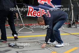 10.07.2009 Nürburg, Germany,  Sebastian Vettel (GER), Red Bull Racing helps out by removing tape from his pit  - Formula 1 World Championship, Rd 9, German Grand Prix, Friday