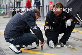10.07.2009 Nürburg, Germany,  Sebastian Vettel (GER), Red Bull Racing helps out by removing tape from his pit - Formula 1 World Championship, Rd 9, German Grand Prix, Friday