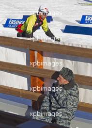 04.03.2011, Khanty-Mansiysk, Russia (RUS): Biathlon Feature: Russian Army member taking a rest in the biathlon stadium while Miroslav Matiasko (SVK), Atomic,  Rottefella, Alpina, Leki passes by - IBU world championships biathlon, training, Khanty-Mansiysk (RUS). www.xpb.cc. Â© Miko/xpb.cc. Every downloaded picture is fee-liable.