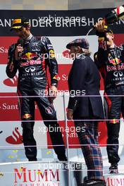 Sebastian Vettel (GER) Red Bull Racing pours champagne on Jackie Stewart (GBR) on the podium as race winner Mark Webber (AUS) Red Bull Racing talks to the crowd. 08.07.2012. Formula 1 World Championship, Rd 9, British Grand Prix, Silverstone, England, Race Day