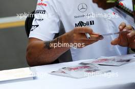 Lewis Hamilton (GBR) McLaren, with new tattoo, signs autographs for the fans. 25.10.2012. Formula 1 World Championship, Rd 17, Indian Grand Prix, New Delhi, India, Preparation Day