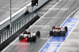 Narain Karthikeyan (IND) HRT Formula One Team HRT F112 leads Jenson Button (GBR) McLaren MP4/27 out of the pits. 25.03.2012. Formula 1 World Championship, Rd 2, Malaysian Grand Prix, Sepang, Malaysia, Sunday Race