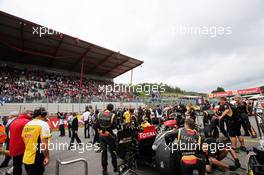 Romain Grosjean (FRA) Lotus F1 E21 on the grid as Greenpeace protesters make a protest against race title sponsors Shell on the roof of the main grandstand. 25.08.2013. Formula 1 World Championship, Rd 11, Belgian Grand Prix, Spa Francorchamps, Belgium, Race Day.