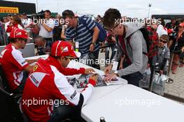 (L to R): Fernando Alonso (ESP) Ferrari and team mate Felipe Massa (BRA) Ferrari sign autographs for the fans. 29.06.2013. Formula 1 World Championship, Rd 8, British Grand Prix, Silverstone, England, Qualifying Day.