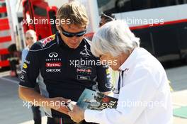 Bernie Ecclestone (GBR) CEO Formula One Group (FOM) signs an autograph for a Red Bull Racing team member. 30.06.2013. Formula 1 World Championship, Rd 8, British Grand Prix, Silverstone, England, Race Day.