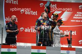 Race winner and World Champion Sebastian Vettel (GER) Red Bull Racing celebrates with the champagne on the podium with Romain Grosjean (FRA) Lotus F1 Team. 27.10.2013. Formula 1 World Championship, Rd 16, Indian Grand Prix, New Delhi, India, Race Day.