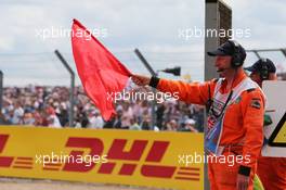 A marshal waves a red flag as the race is stopped. 06.07.2014. Formula 1 World Championship, Rd 9, British Grand Prix, Silverstone, England, Race Day.