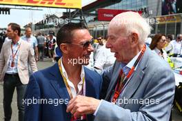 (L to R): Frankie Dettori (ITA) Jockey with John Surtees (GBR) on the grid. 05.07.2015. Formula 1 World Championship, Rd 9, British Grand Prix, Silverstone, England, Race Day.