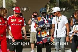(L to R): Kimi Raikkonen (FIN) Ferrari with Mr Moko (SEN) Crown Hearts Jewelry and Lewis Hamilton (GBR) Mercedes AMG F1. 26.11.2015. Formula 1 World Championship, Rd 19, Abu Dhabi Grand Prix, Yas Marina Circuit, Abu Dhabi, Preparation Day.