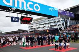 (L to R): George Russell (GBR) Mercedes AMG F1; Lewis Hamilton (GBR) Mercedes AMG F1; and Lando Norris (GBR) McLaren as the grid observes the national anthem. 09.07.2023. Formula 1 World Championship, Rd 11, British Grand Prix, Silverstone, England, Race Day.